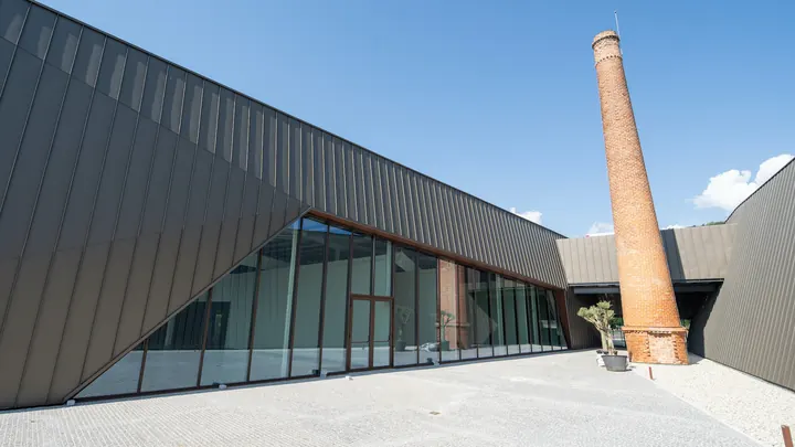 Edifício industrial reconvertido com chaminé de tijolo e fachadas em zinco